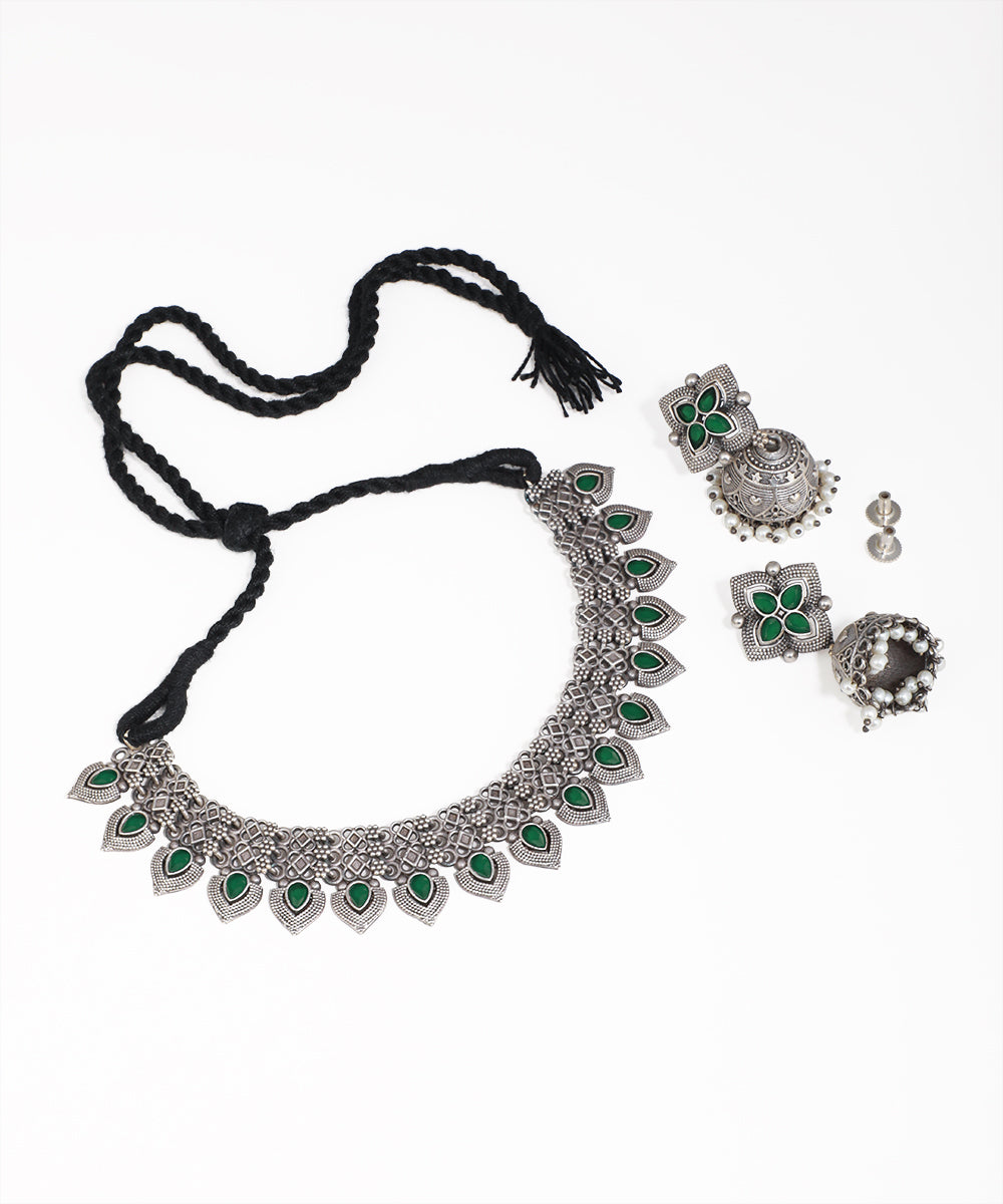 Silver necklace with green stones and matching earrings on a white background