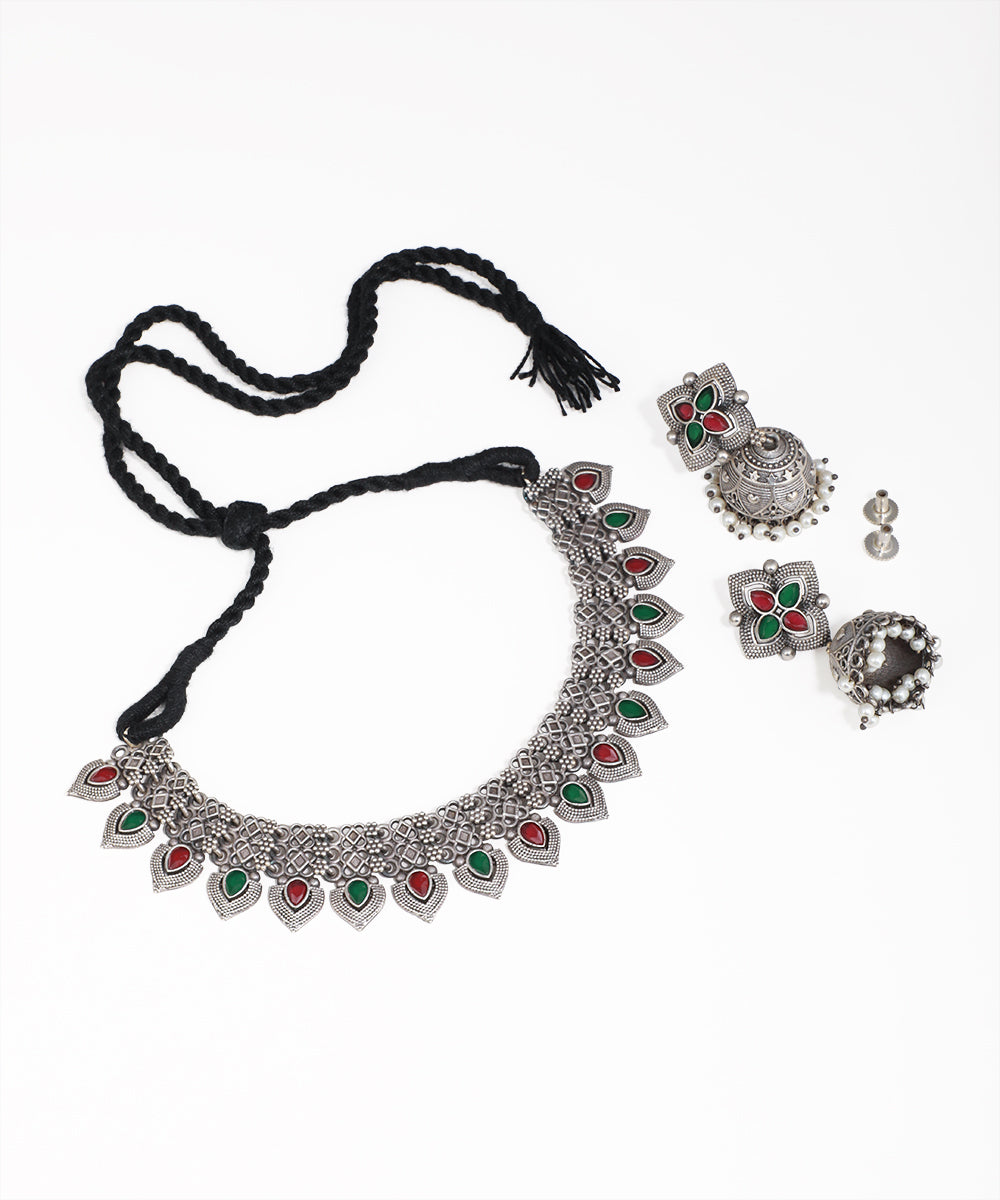 Silver necklace with green and red stones and matching earrings on a white background