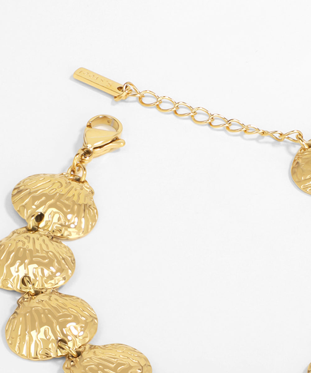 Gold bracelet with shell-like charms on a white background