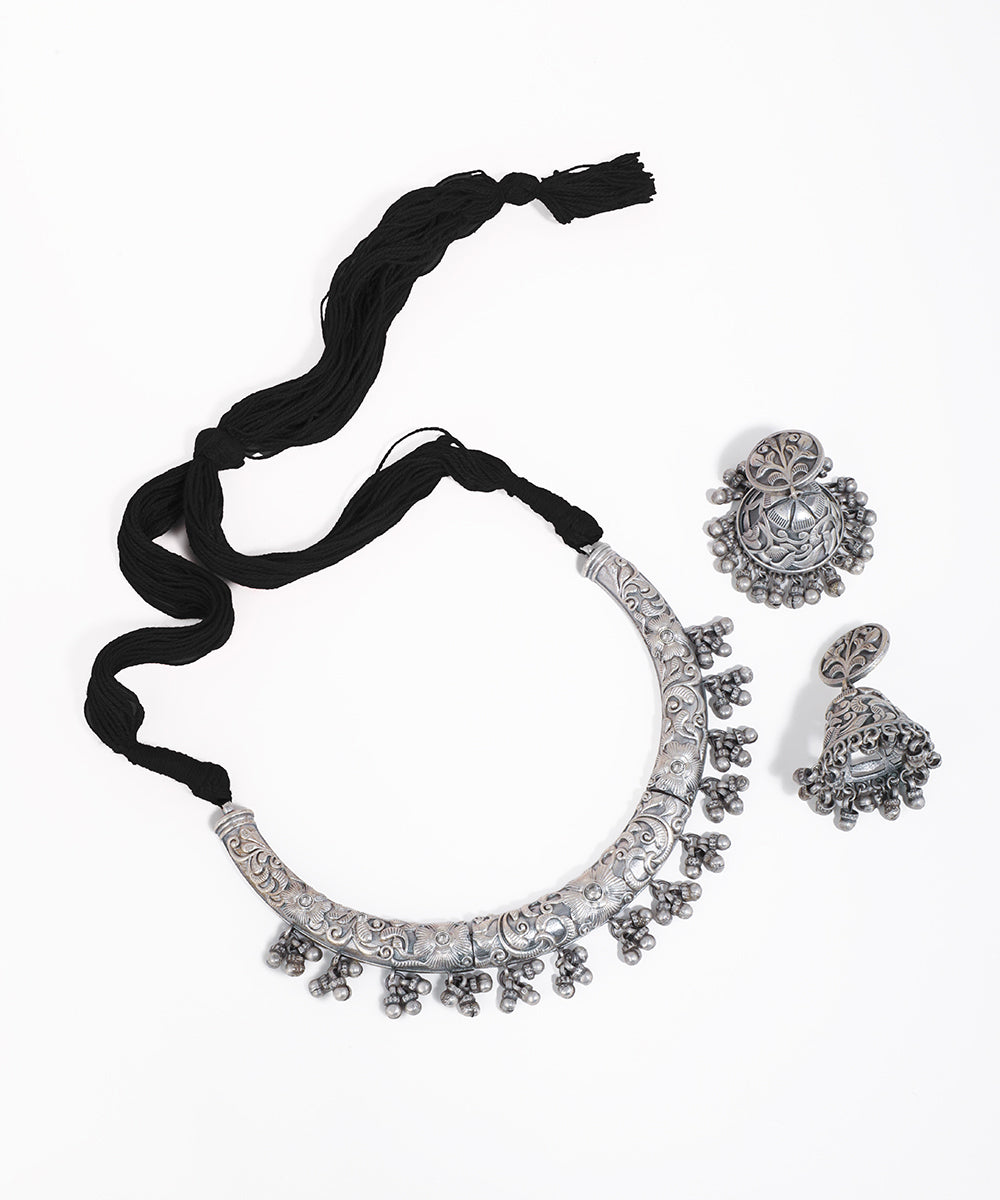 Silver necklace and earrings set with black ribbon on a white background