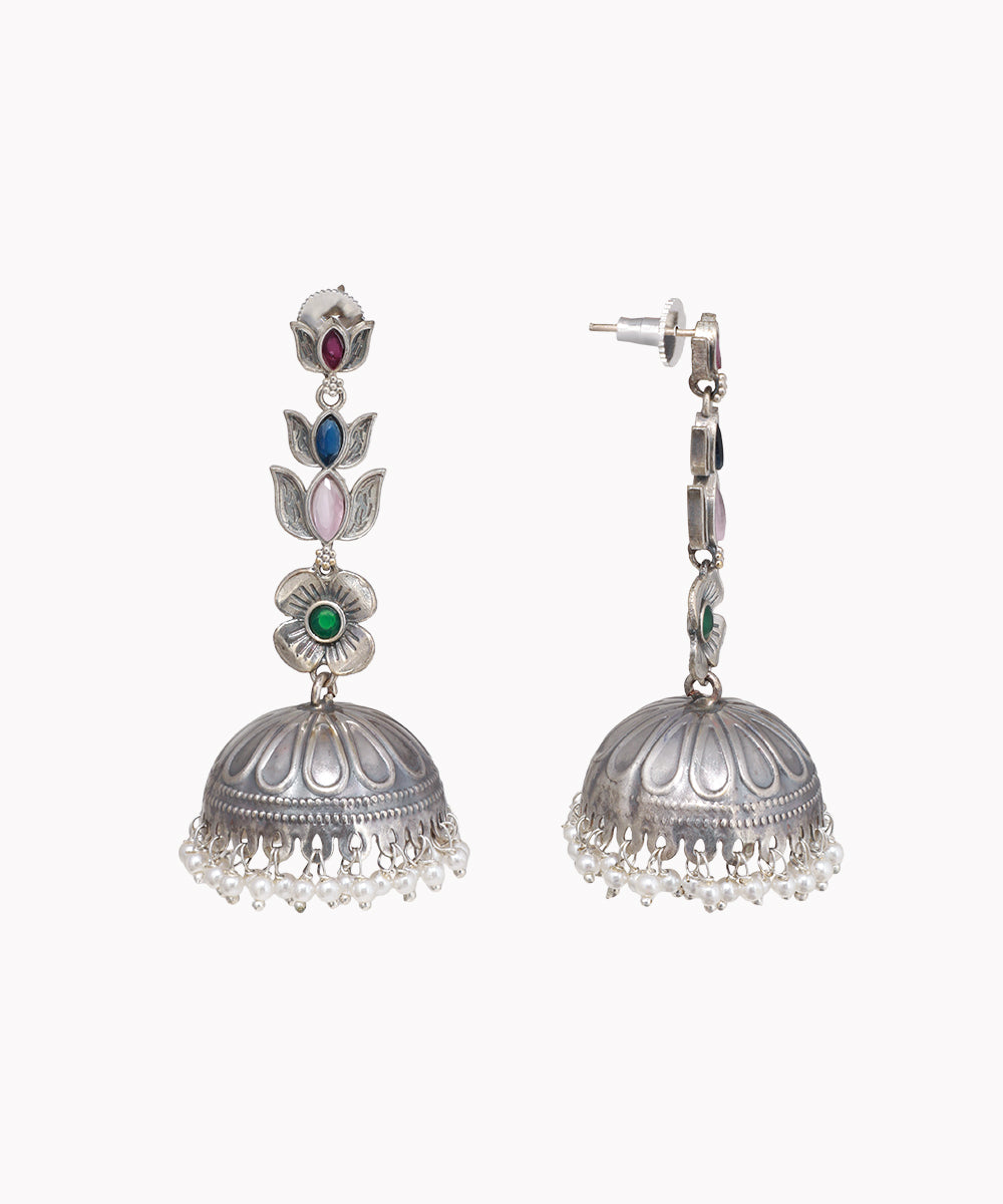 Oxidized silver-tone drop earrings with colorful floral motifs, green center crystal, and faux pearl jhumka bells.