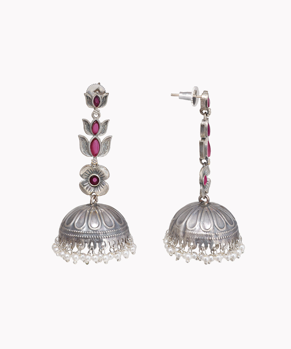 Pair of silver jhumka earrings with pink gemstones on a white background