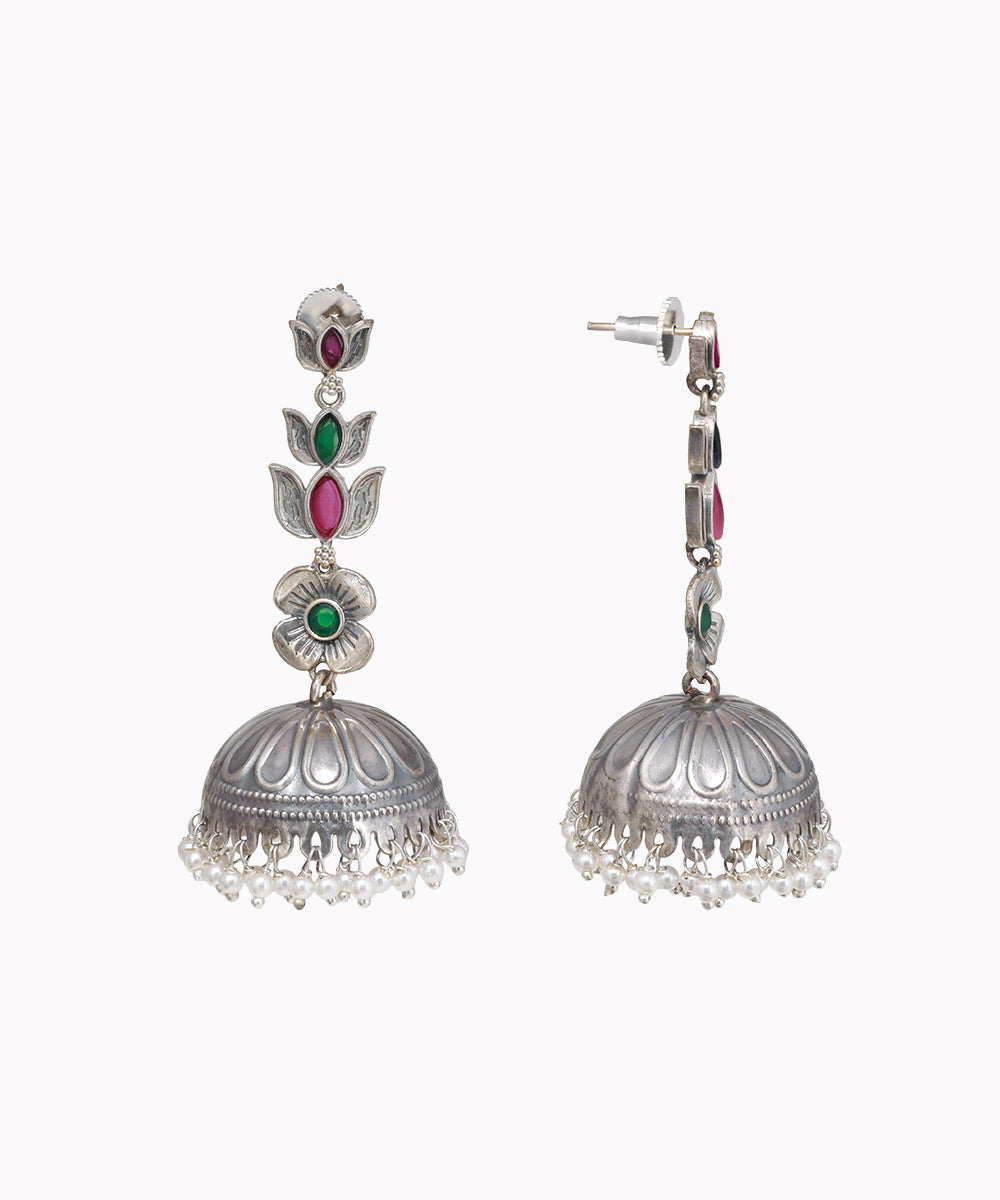 Pair of silver jhumka earrings with gemstones on a white background