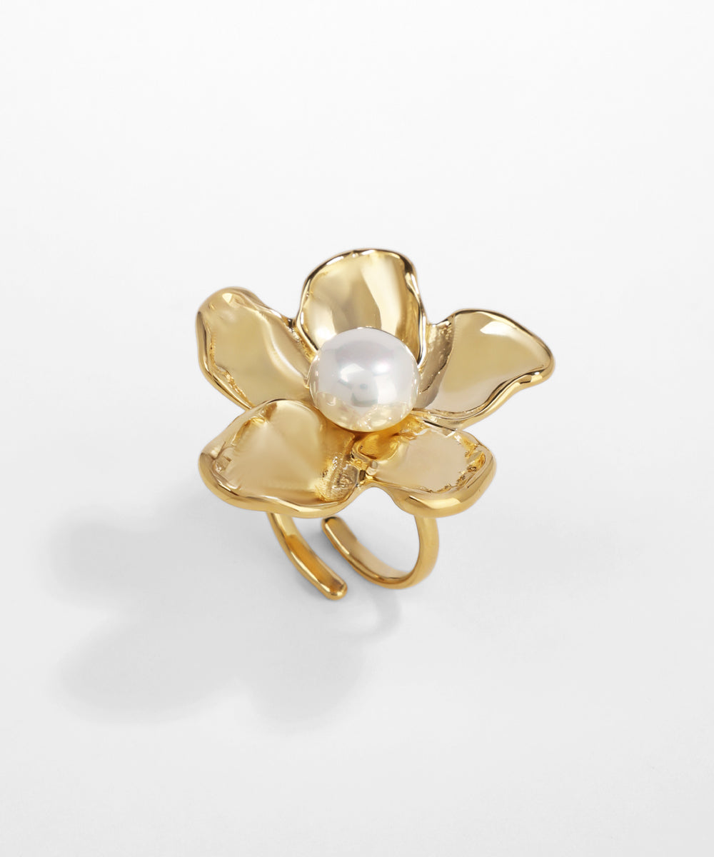 Gold flower-shaped ring with a pearl center on a light gray background