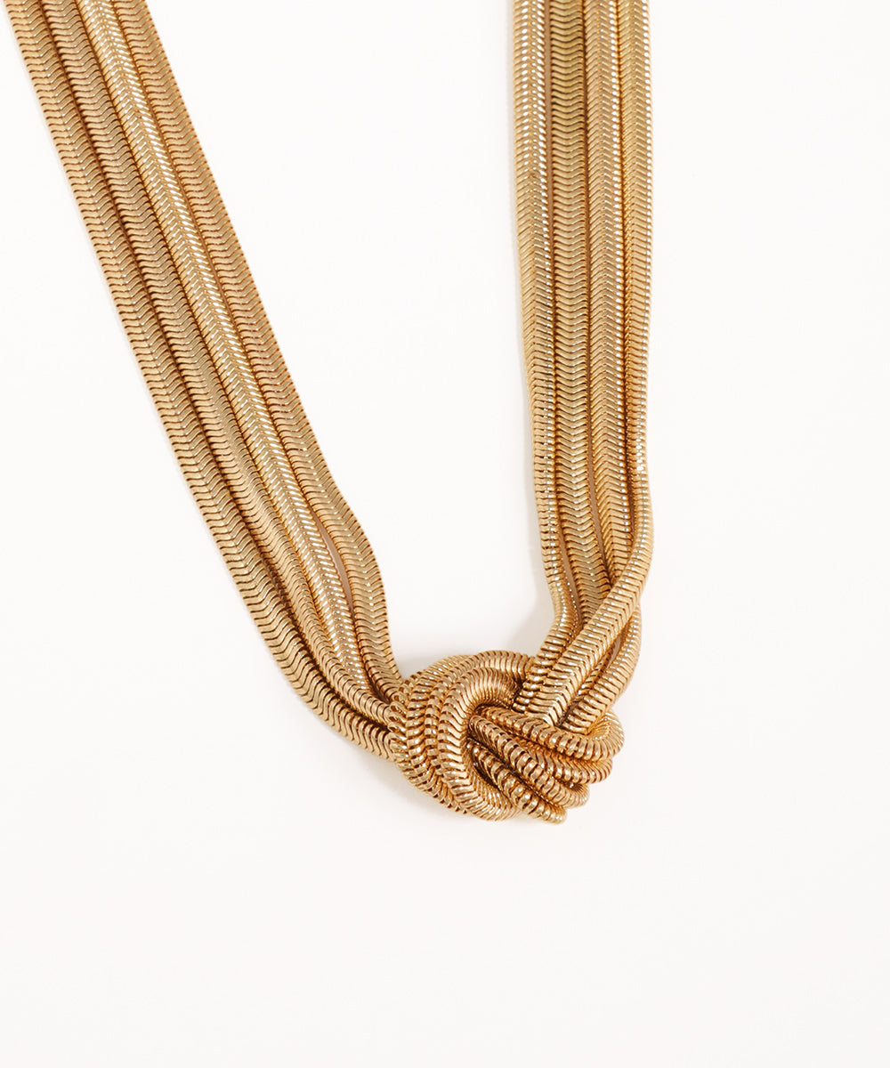 Gold rope-style necklace on a white background