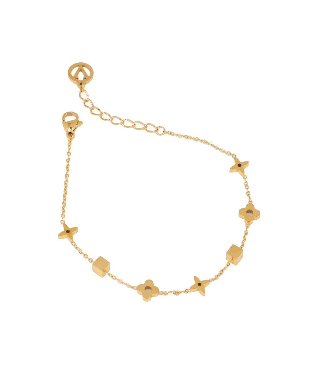 Gold-tone bracelet with alternating geometric cube and four-petal floral charms on a delicate chain.