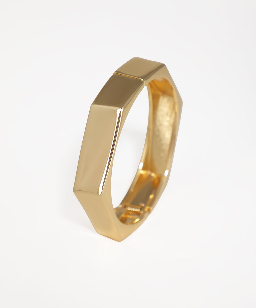 Gold ring with geometric design on a white background
