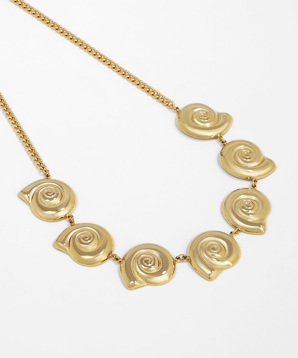 Gold necklace with spiral design on a white background