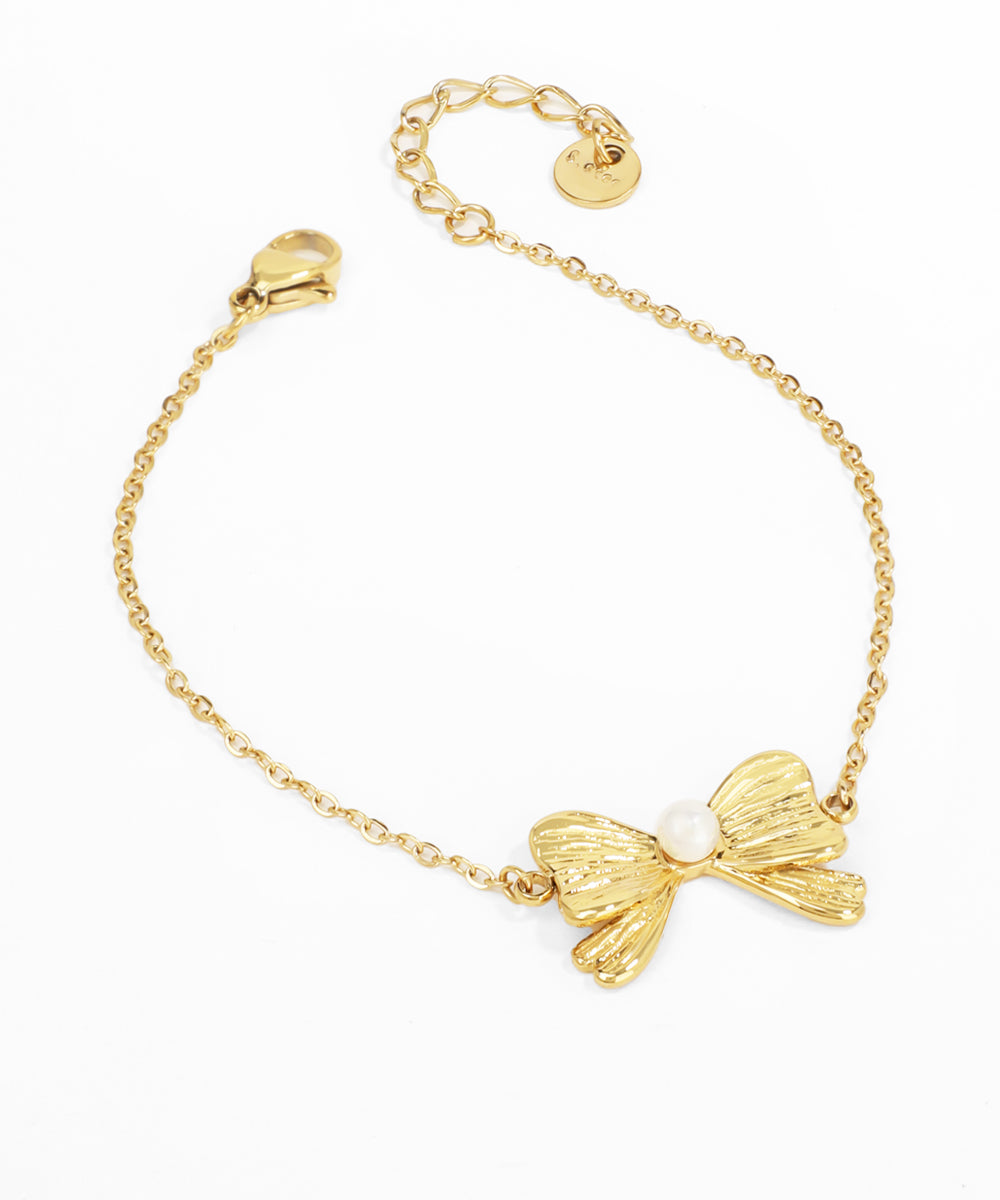 Gold bracelet with a bow-shaped charm on a white background