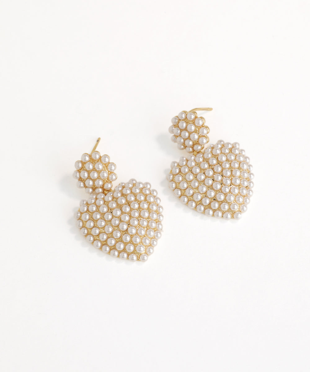 Pair of gold and pearl drop earrings on a white background
