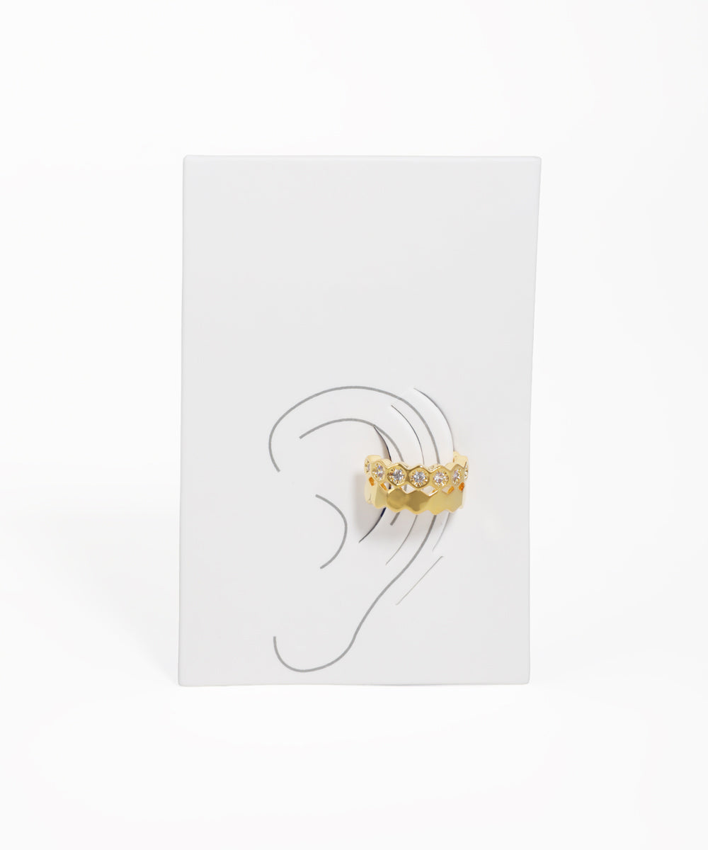 Gold earring displayed on a white card with an ear illustration