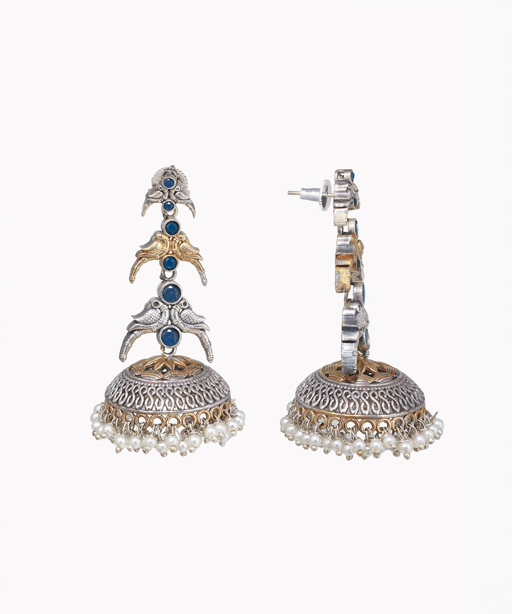 Pair of ornate earrings with blue stones and pearl-like elements on a white background