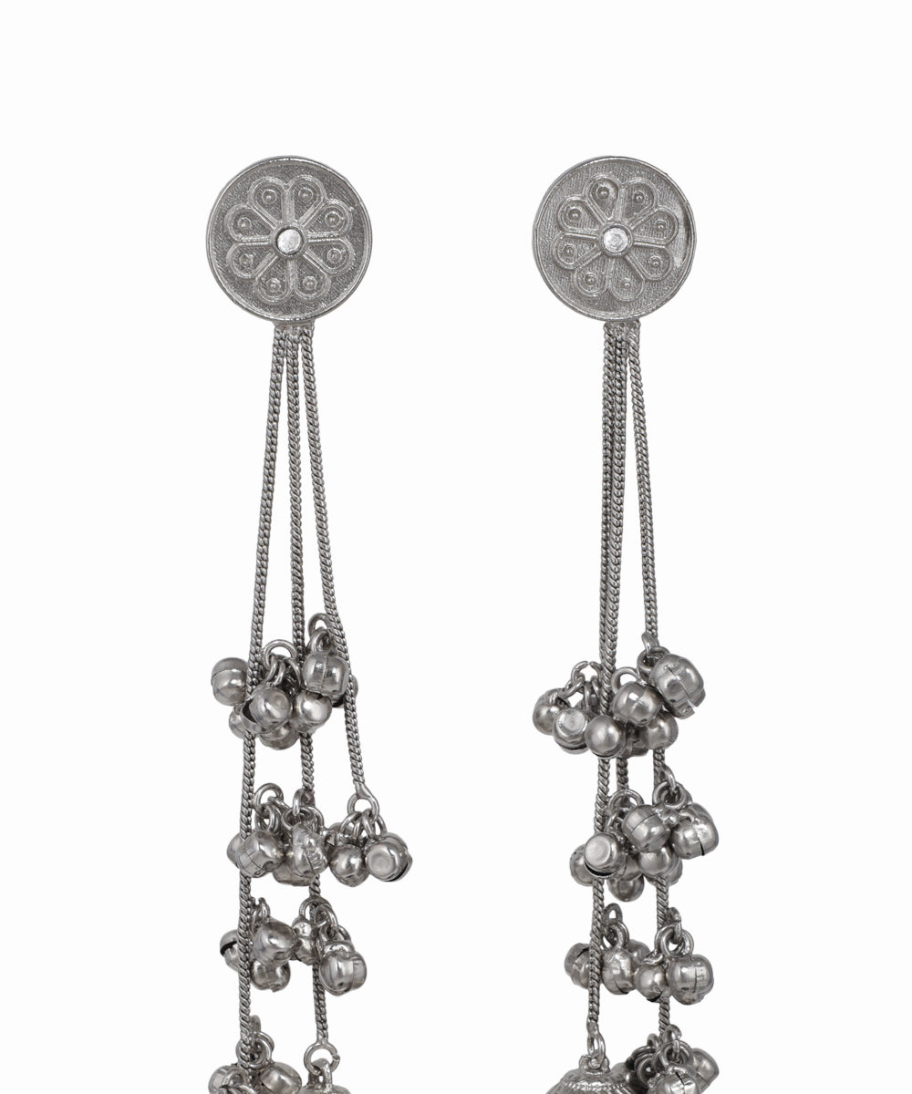 Silver earrings with intricate designs and dangling beads on a white background