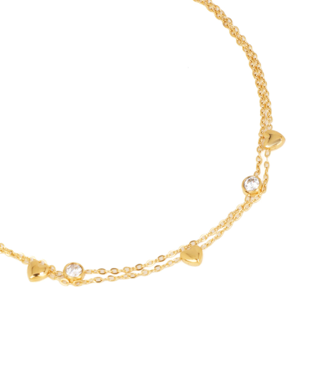 Gold bracelet with heart and clear gemstone charms on a white background