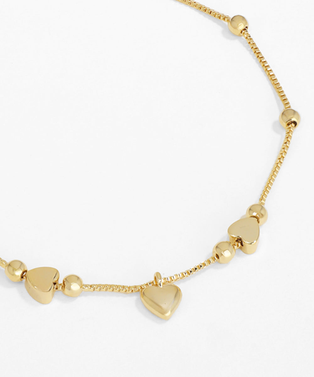 Gold necklace with heart-shaped pendants on a white background