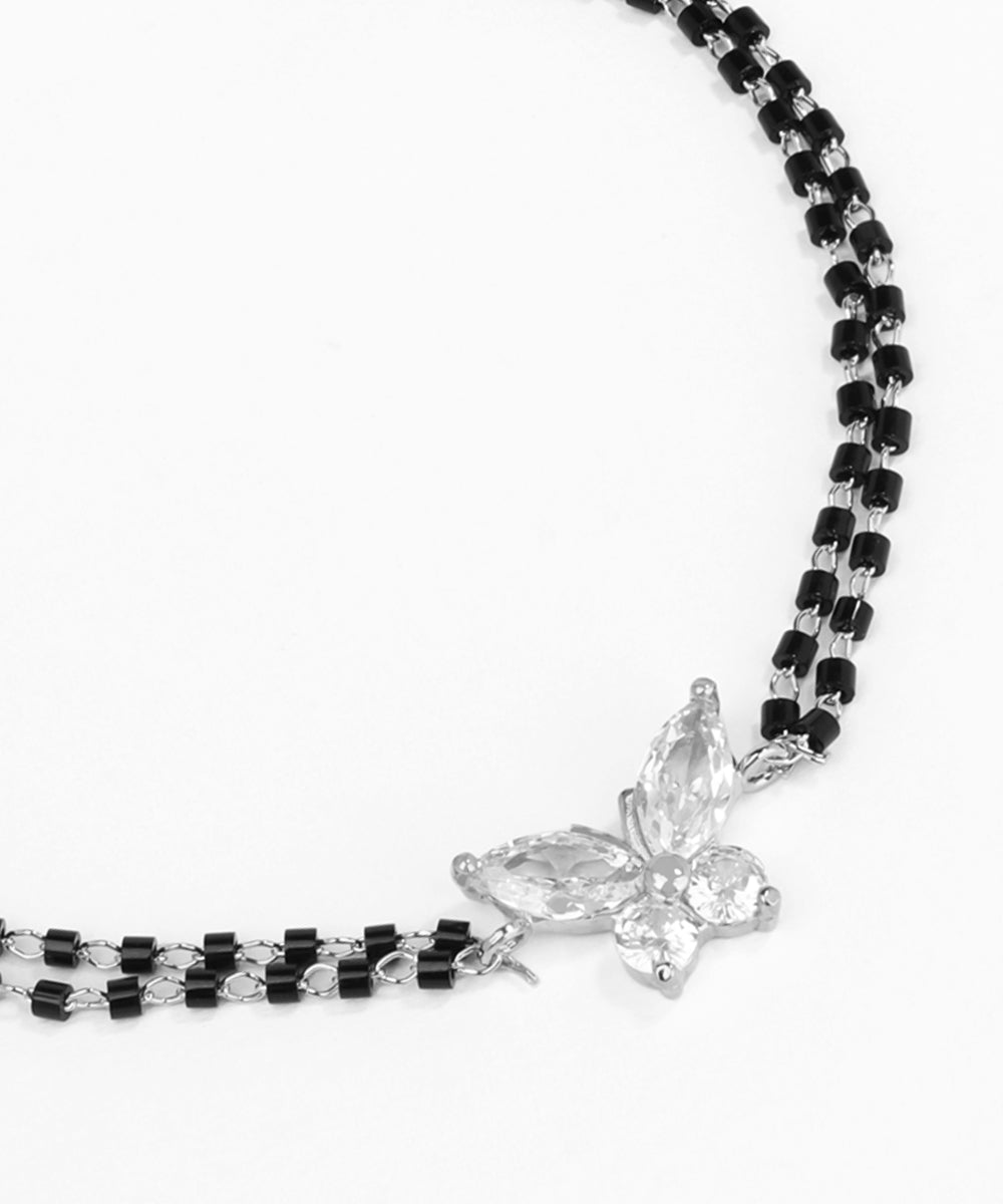 Black beaded necklace with a silver butterfly pendant on a white background