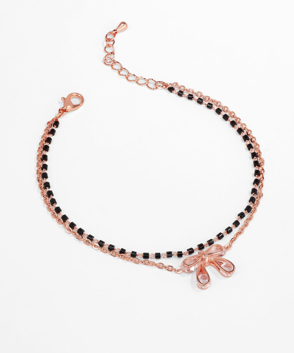 Rose gold bracelet with black beads on a white background