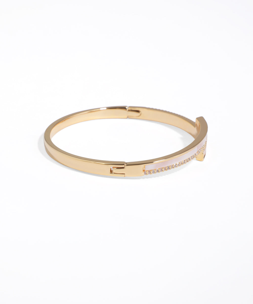Gold bangle with pink interior on a white background
