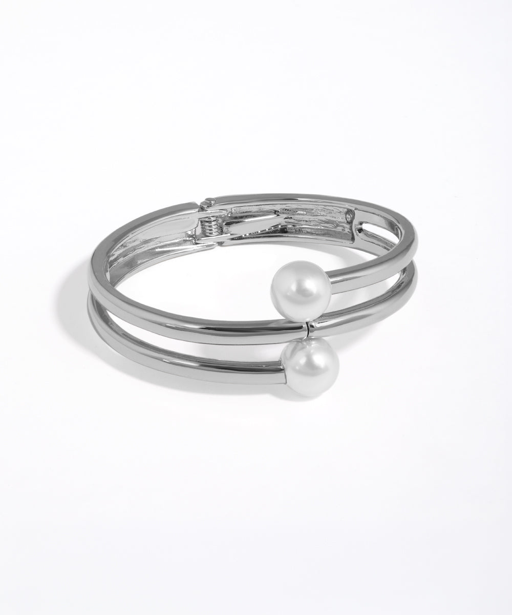 Silver bracelet with pearl accents on a white background
