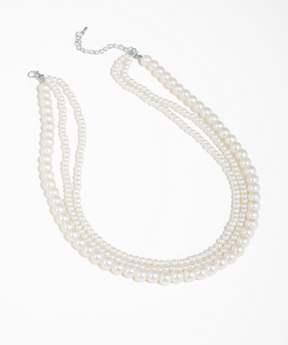 Silver-tone necklace with three layered strands of graduated faux pearls.