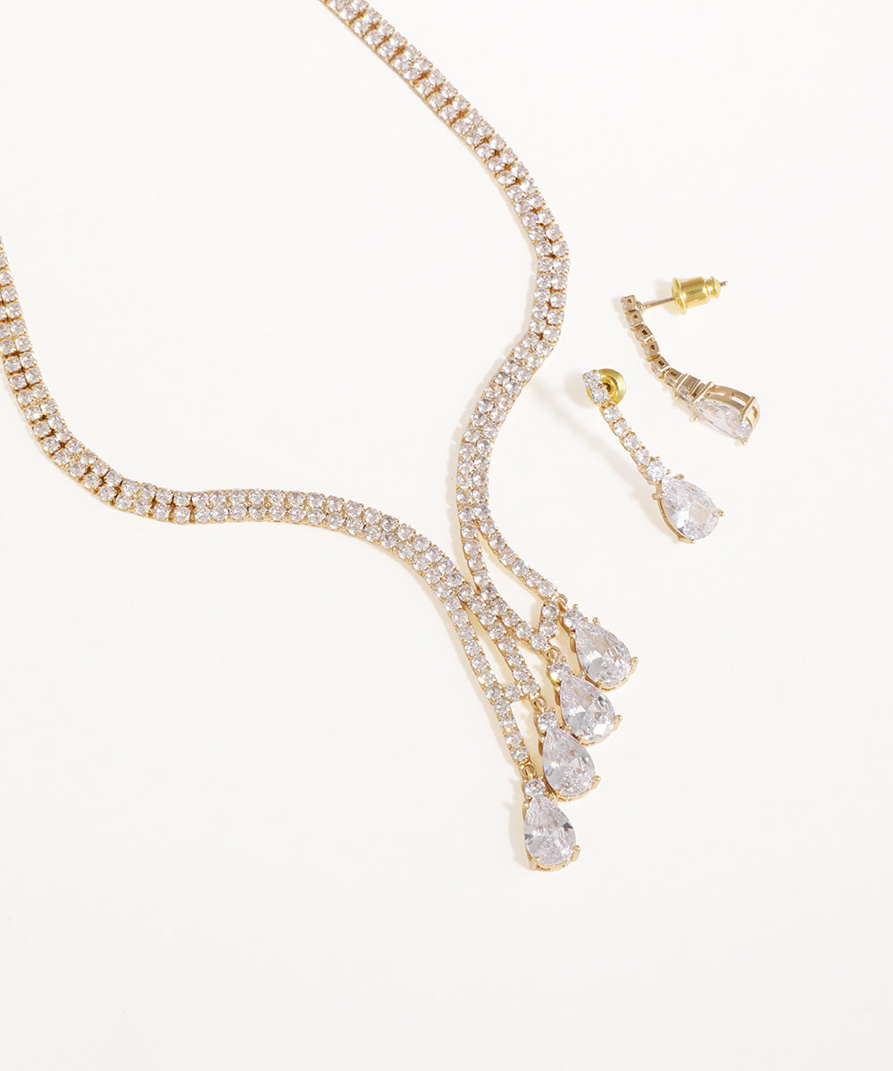Gold necklace and earrings with clear stones on a white background