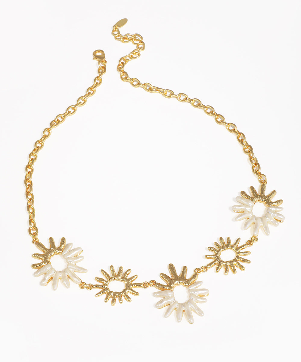 Gold-tone necklace with alternating sunburst motifs and white shell-inspired inlay on a chain