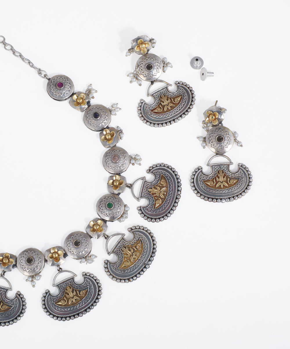 Ornate silver and gold necklace with intricate designs on a white background