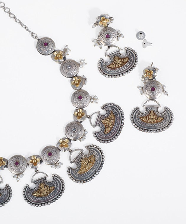 Ornate silver necklace with matching earrings on a white background
