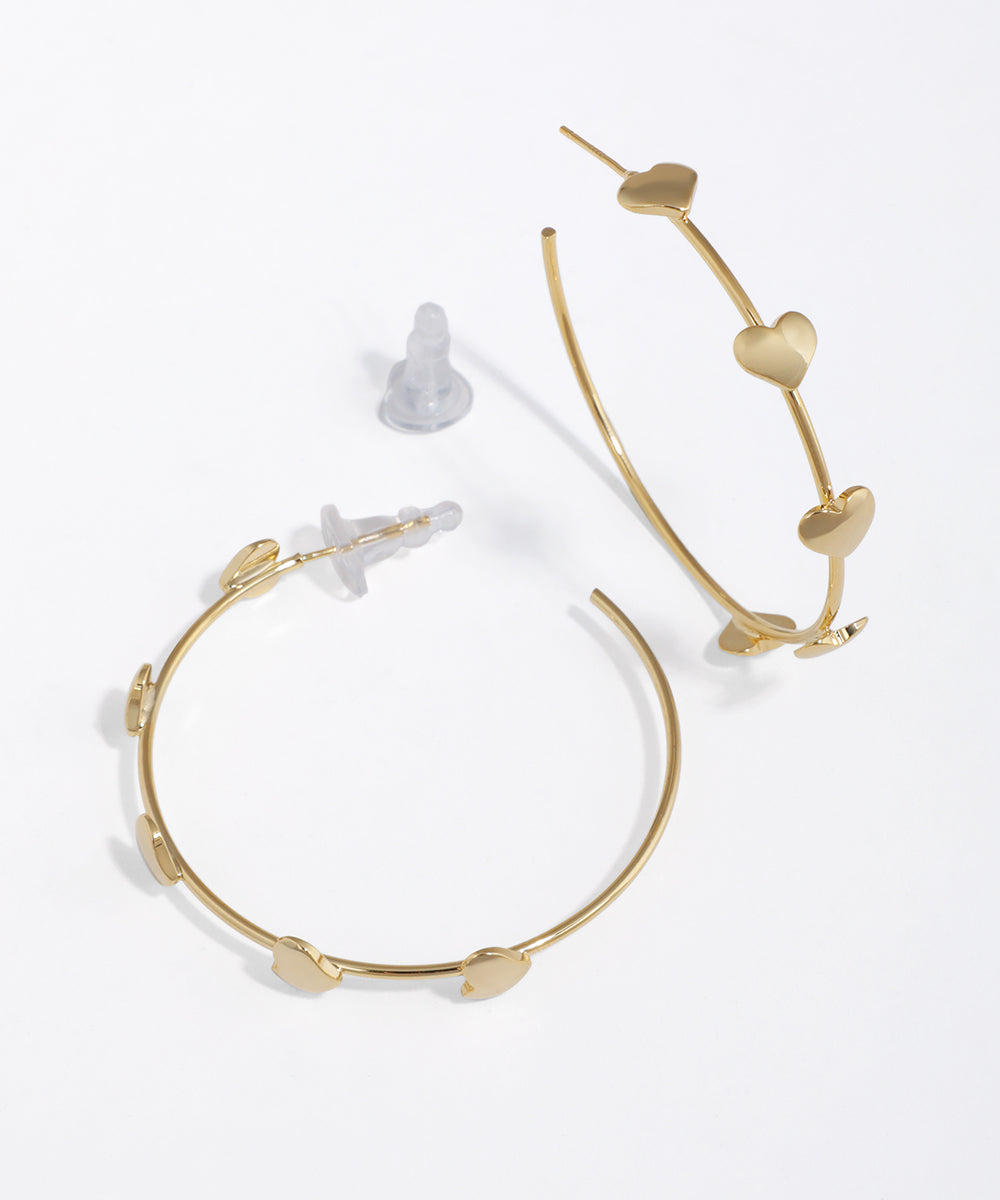 Gold-tone hoop earrings with flat, sculpted heart details and push-back closure.