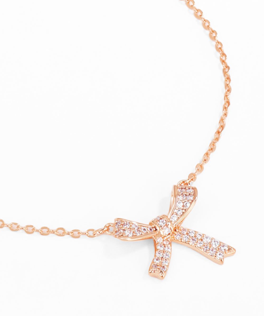Rose gold necklace with a cross pendant on a white background Pookie
