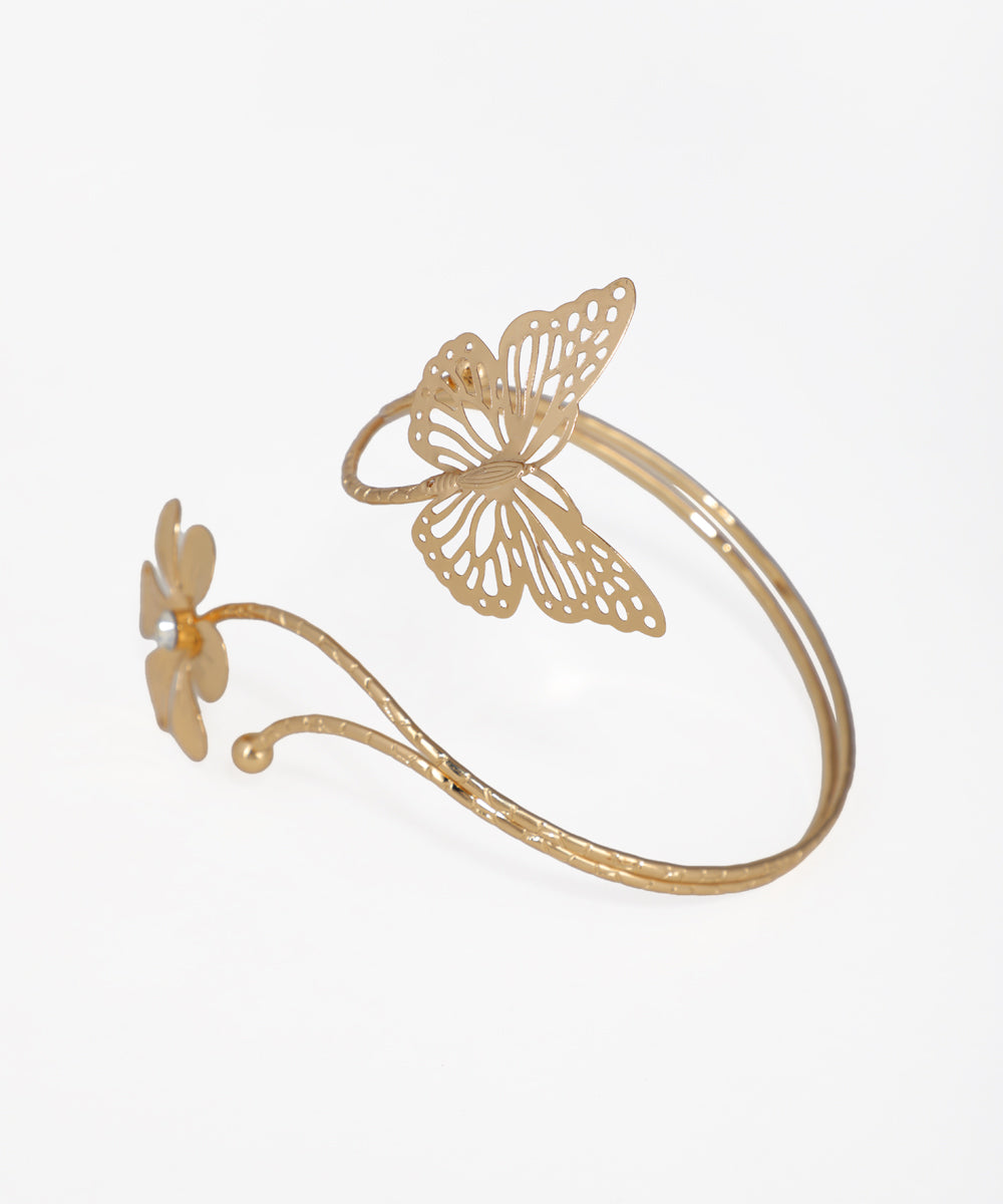 Gold-tone arm cuff with a large filigree butterfly and a small flower with a faux pearl center.
