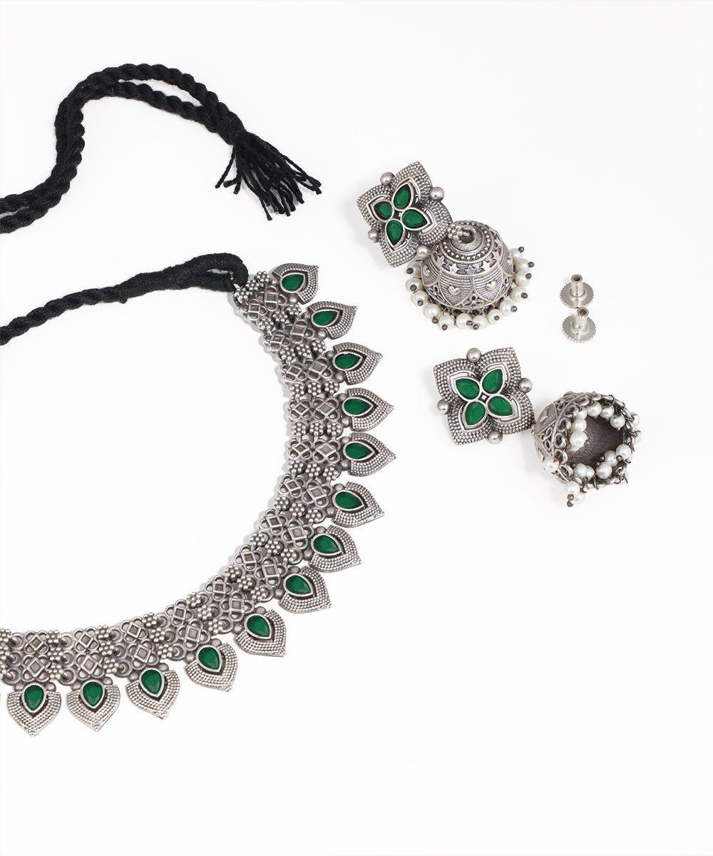 Silver jewelry set with green stones on a white background