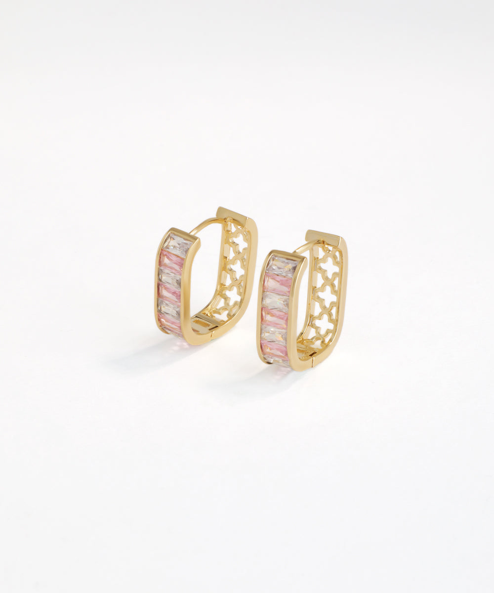 Gold hoop earrings with pink gemstones on a white background