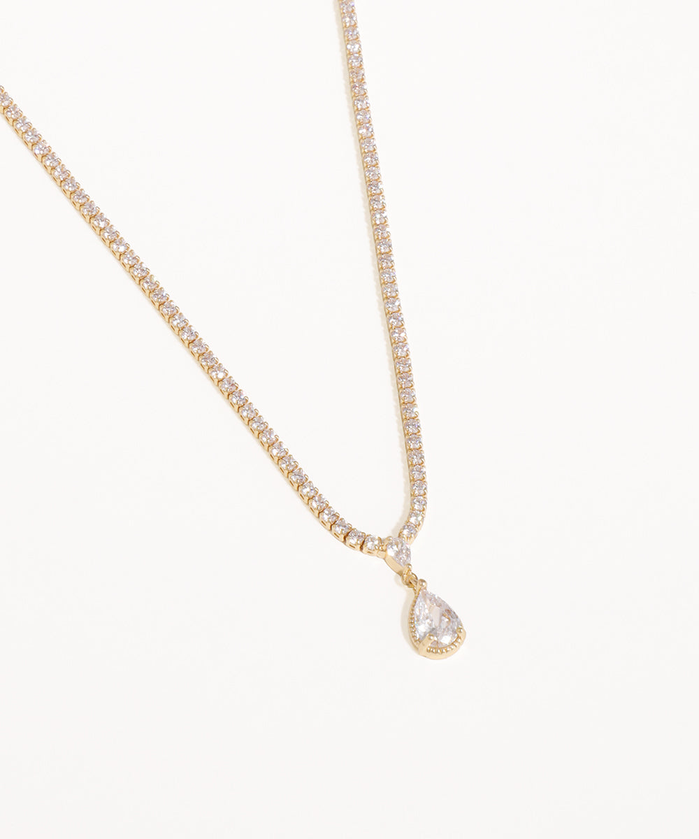 Gold necklace with a teardrop-shaped diamond pendant on a white background