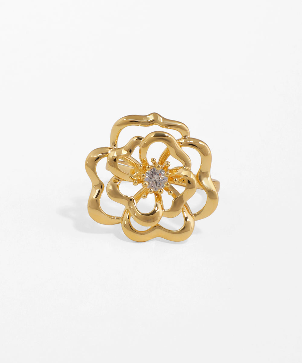 Gold flower-shaped ring with a diamond on a white background