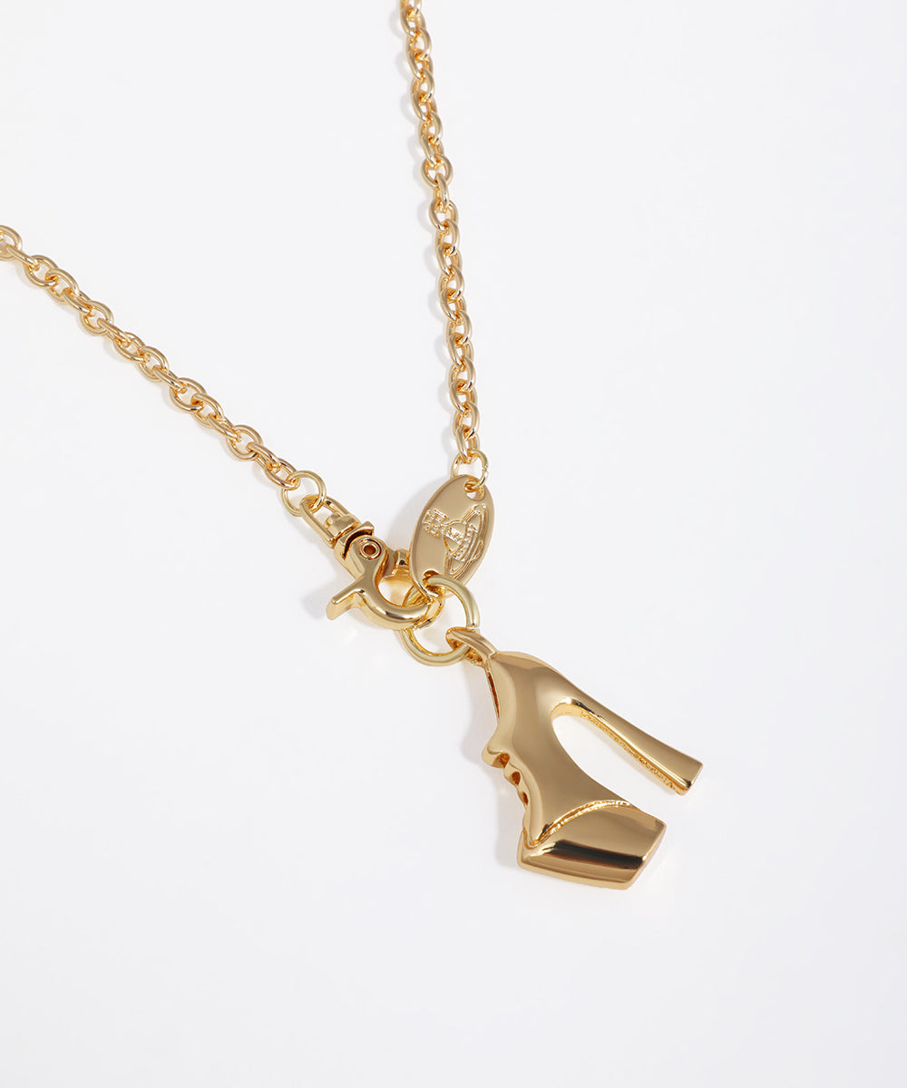 Gold high-heeled shoe pendant on a chain against a white background