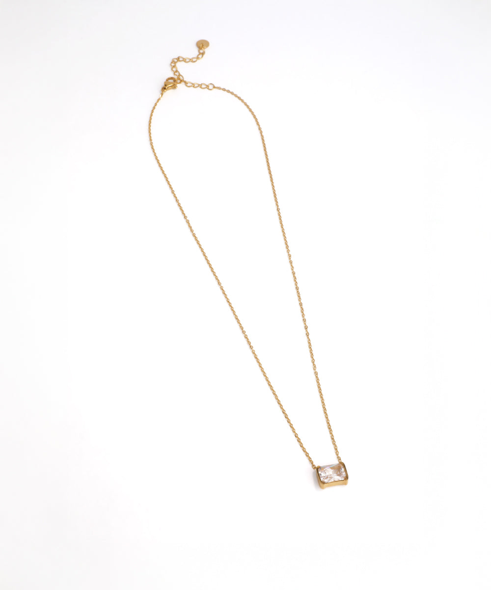 Gold necklace with a clear pendant on a white background