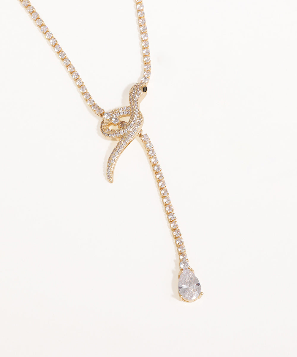 Gold necklace with a teardrop pendant on a white background