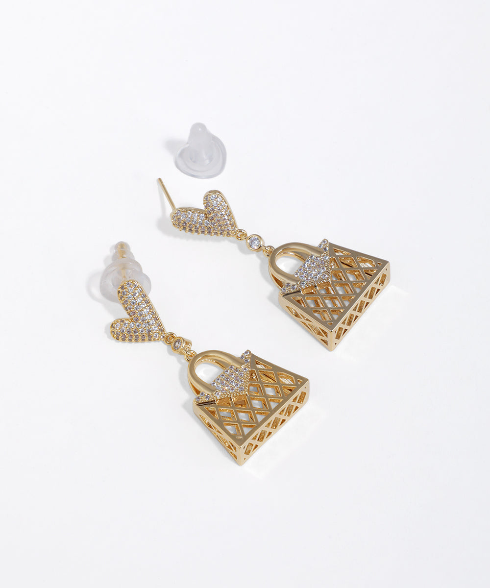 Gold-tone dangle earrings with heart studs and lattice basket-shaped drops, adorned with clear CZ stones.
