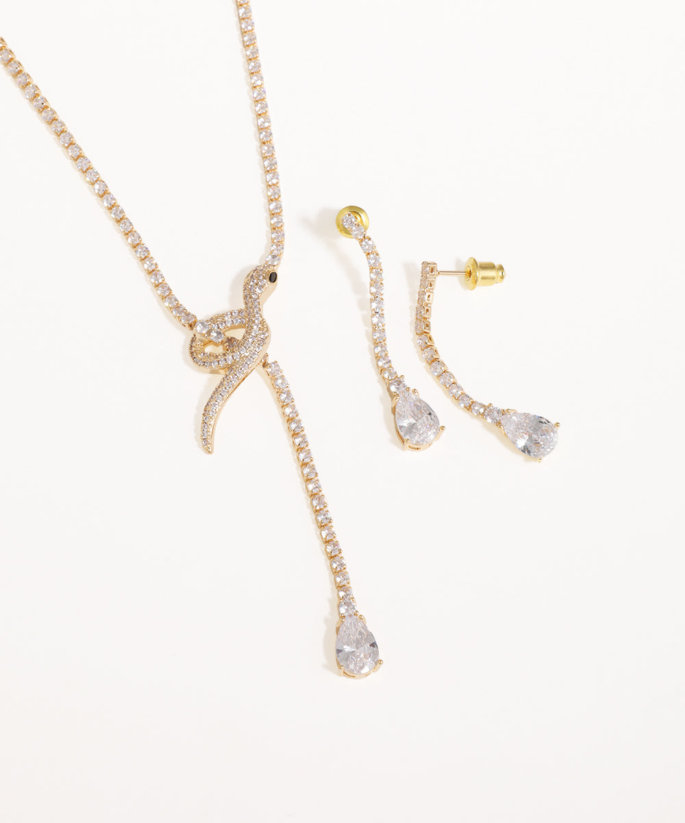 Gold necklace and earrings with clear stones on a white background