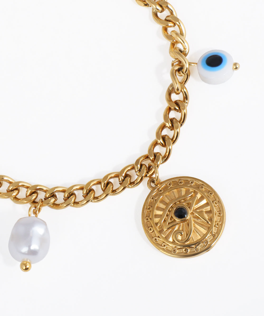 Gold chain bracelet with decorative charm and pearl on a white background
