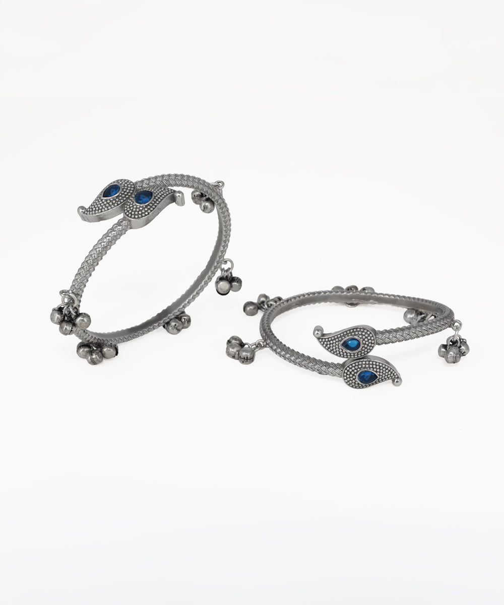 Pair of silver bangles with blue stones on a white background