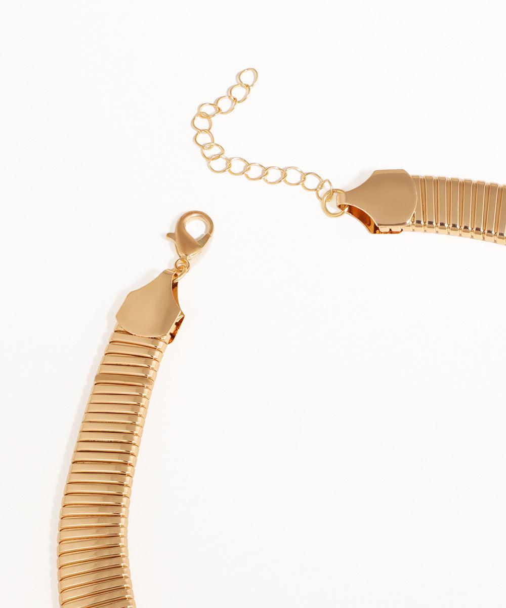 Gold bracelet with a textured design on a white background