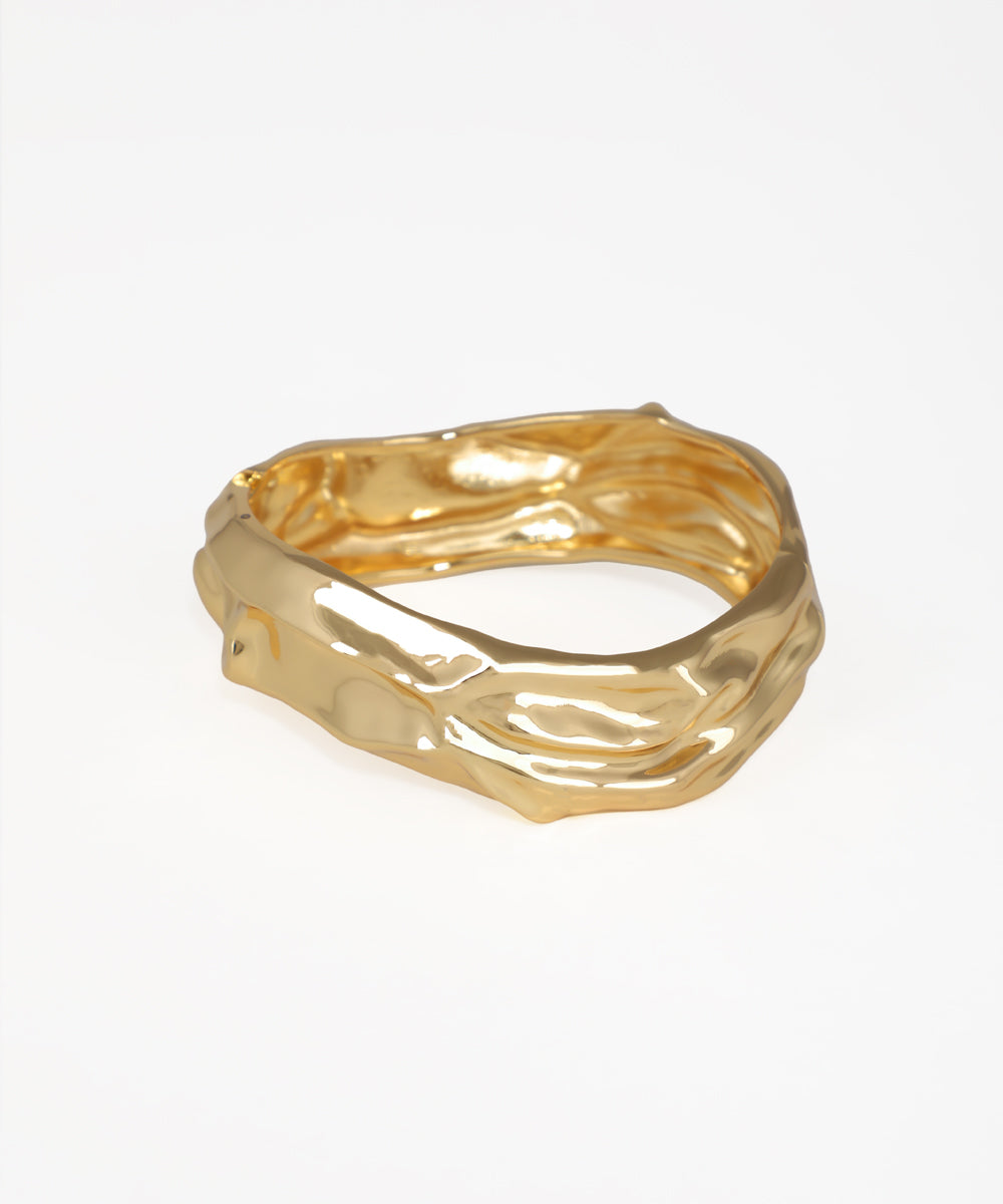 Gold ring with a textured design on a white background