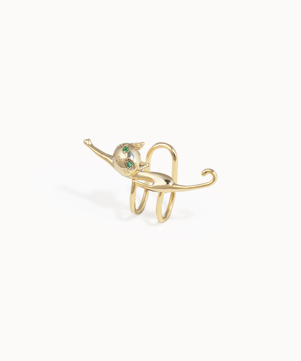 Gold elephant-shaped ring with green gemstones on a white background
