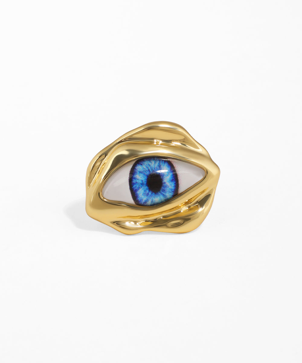 Gold-tone ring with a wavy, sculptural band featuring a realistic blue eye motif