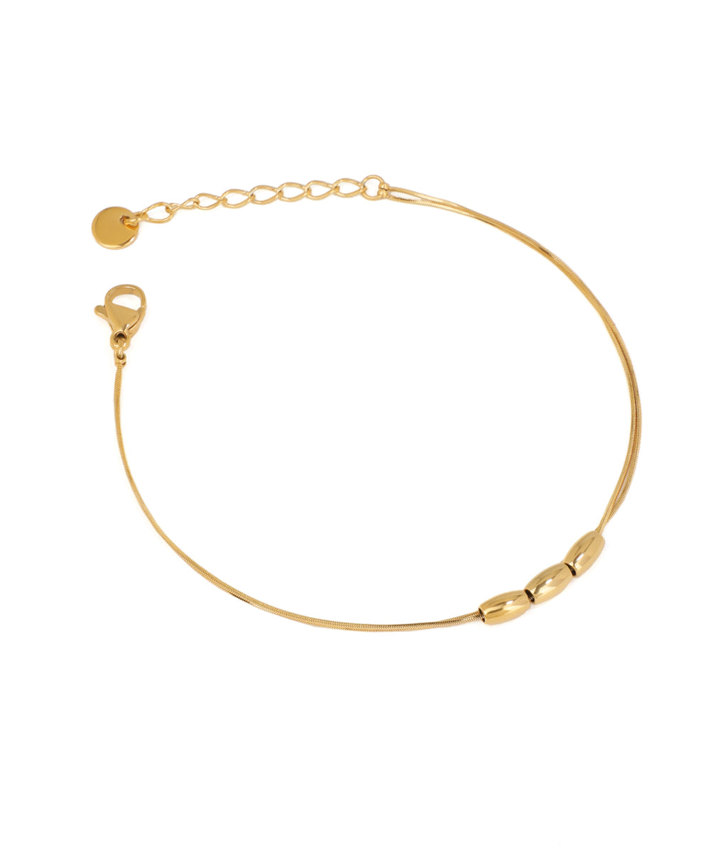 Gold-tone bracelet with a slender snake chain and three polished oval beads.