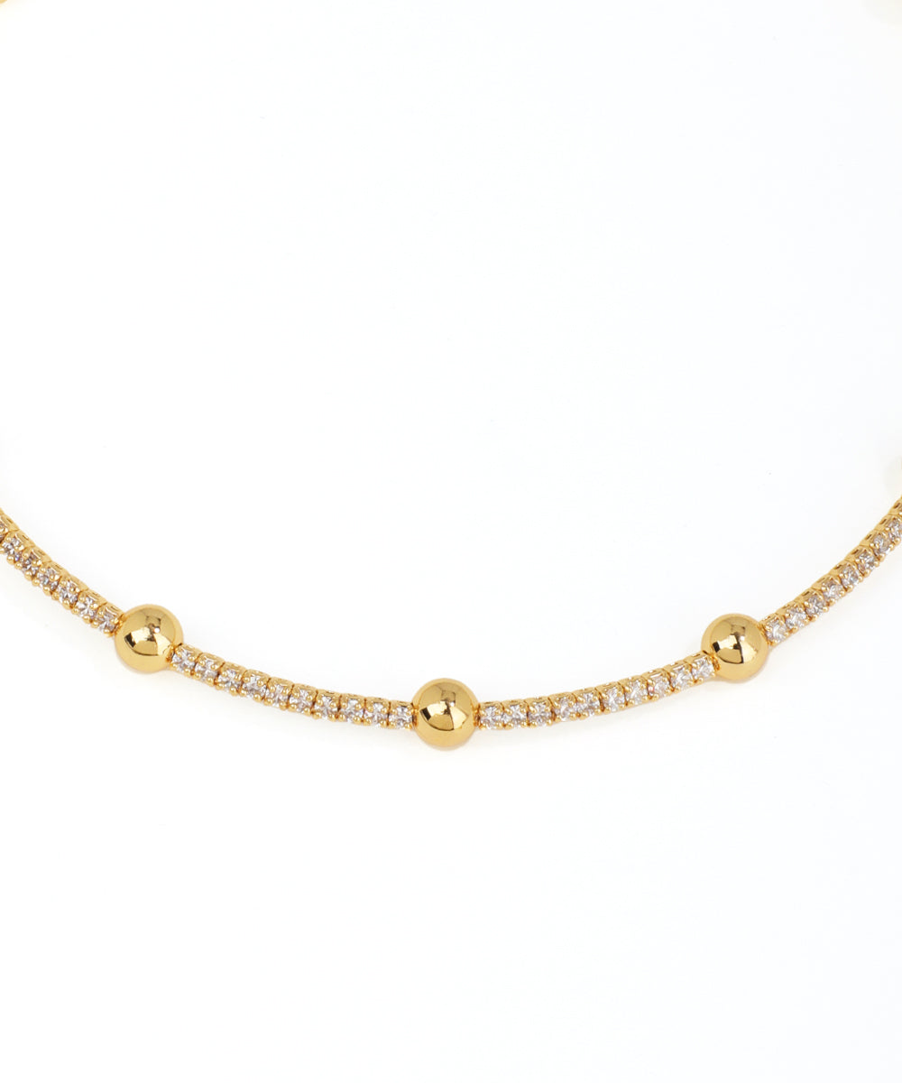 Gold necklace with small beads on a white background