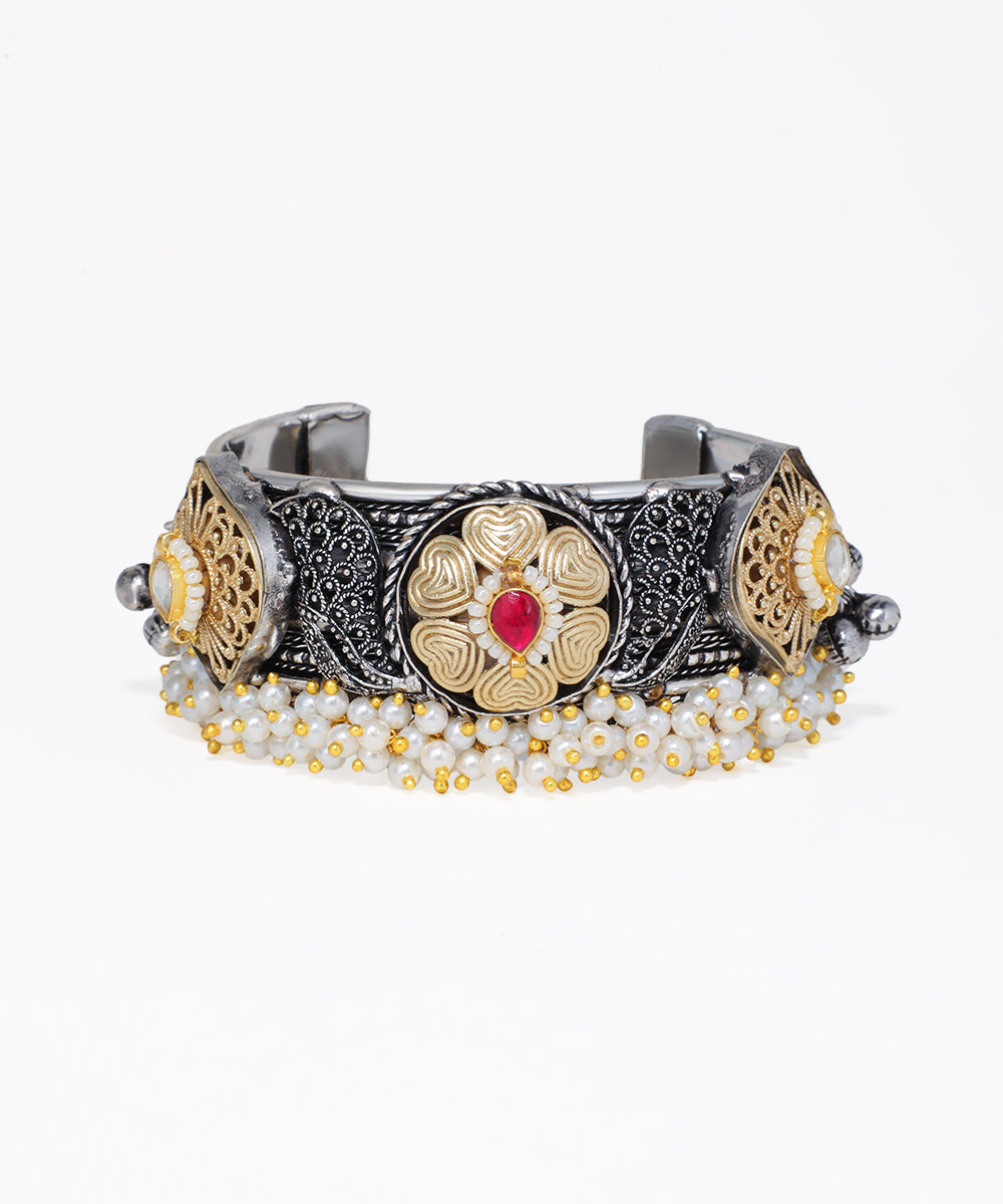 Decorative bracelet with intricate designs and a red gemstone on a white background