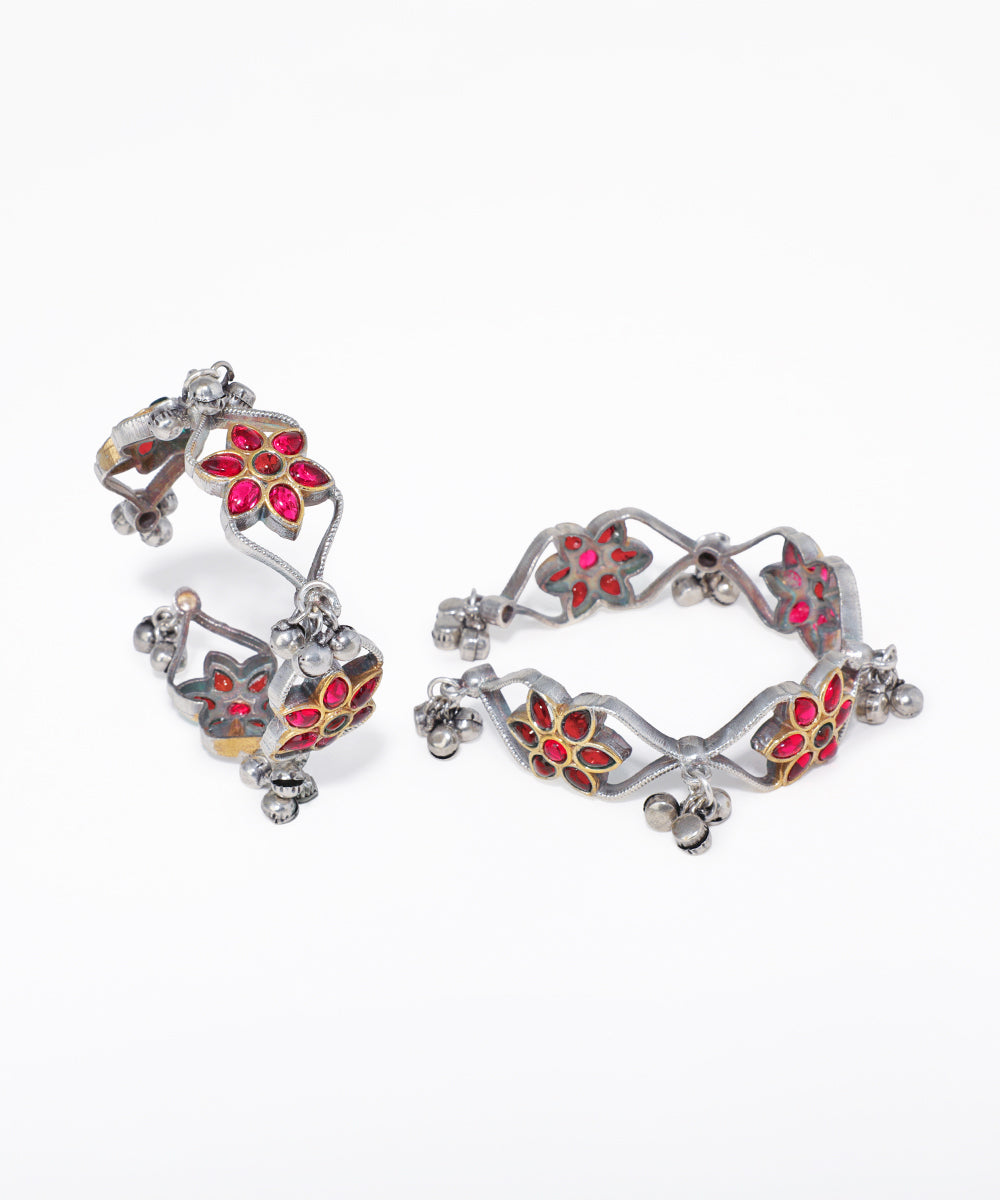 Pair of silver earrings with red and gold floral designs on a white background